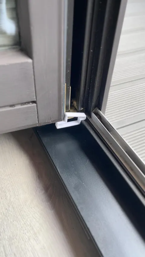 Fensterstopper von Slick: weißer Stopper klemmt unten zwischen Fensterrahmen und Flügel