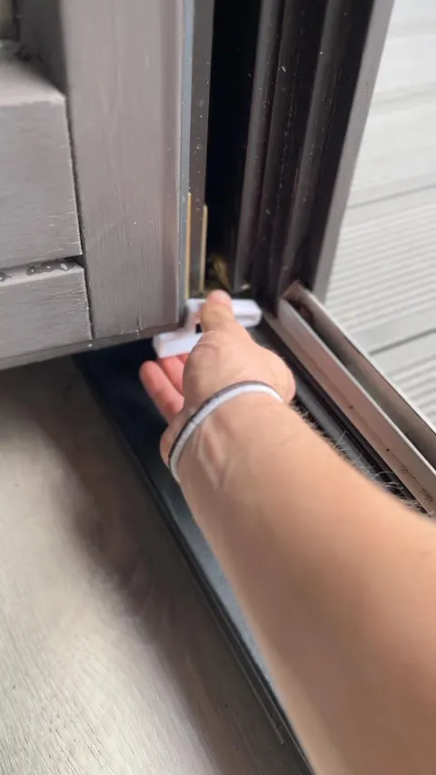 Fensterstopper von Slick: Hand setzt den weißen Stopper zwischen Rahmen und Flügel ein